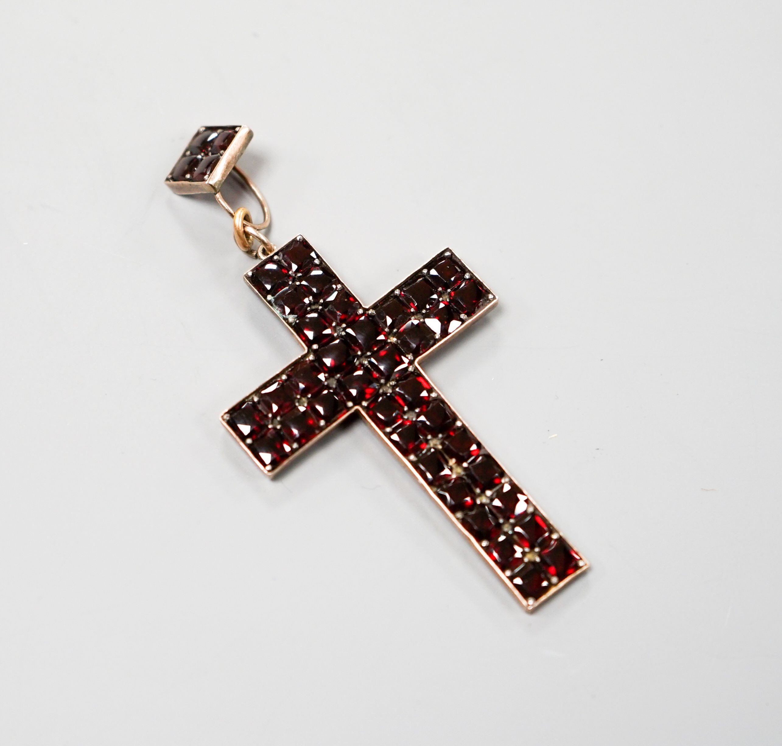 A yellow metal and pave set garnet cross pendant, overall 69mm, gross weight 6.7 grams.